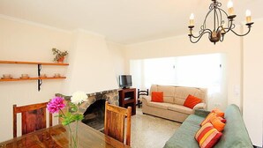 A living room with a fireplace, a dining table, a sofa, and a TV.