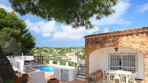 A rooftop terrace with a swimming pool, outdoor seating, and a stone wall with a sign.