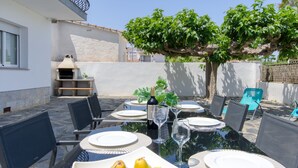 An outdoor dining area with a table set for four, surrounded by chairs. There is a bowl of fruit in the center of the table. - Sant Mori by Interhome (Empuriabrava)