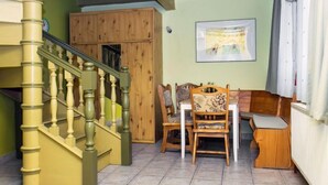 A staircase with wooden balusters, a dining area with wooden chairs and a table, and a framed picture on the wall. - Cortaderia 1 by Interhome (Keszthely/Balatonkeresztur)