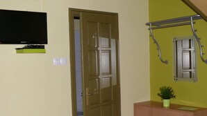 A room with a wooden door, a small cabinet, a television mounted on the wall, and a window with a metal frame. - Cortaderia 1 by Interhome (Keszthely/Balatonkeresztur)