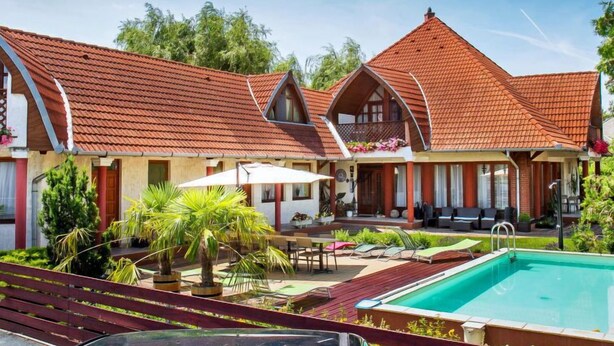 A two-story building with a red-tiled roof, a swimming pool, and outdoor seating. - Cortaderia 1 by Interhome (Keszthely/Balatonkeresztur)