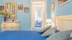 A bedroom with a blue bedspread, a white dresser, and a mirror with a gold frame.