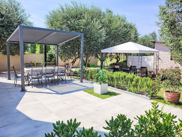 An outdoor patio with a covered seating area, a white tent, and various potted plants. - Vacation home Ive by Interhome (Petrcane)