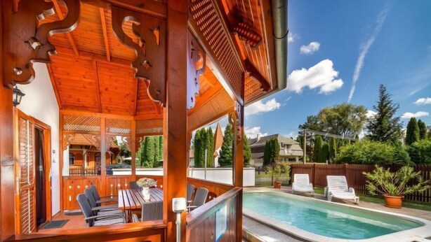 Eine Holzterrasse mit Pool, Sitzgelegenheiten im Freien und Blick auf die Nachbarschaft.