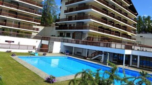 A multi-story hotel with balconies, a swimming pool, and a well-maintained lawn. - Valdor A 42 Sud by Interhome (Crans-Montana)