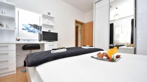 Een moderne hotelkamer met een bed, een bureau met een computer, een televisie en een ontbijttafel op het bed.