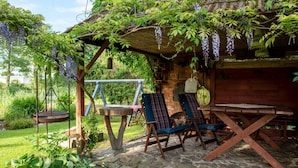 A rustic outdoor seating area with a swing, a wooden table, and chairs under a pergola covered with vines. - Apartment Rekowo by Interhome (Rekowo)