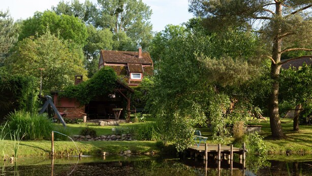 A rustic house with a pond, surrounded by lush greenery and trees. - Apartment Rekowo by Interhome (Rekowo)