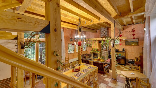 Un intérieur rustique en bois, avec un coin repas, un escalier en bois et une cheminée.