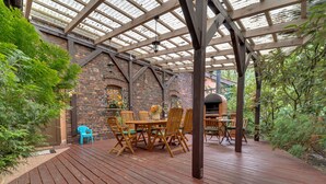 Une terrasse extérieure dotée d’un plancher en bois, d’un mur en briques et d’une pergola en bois.