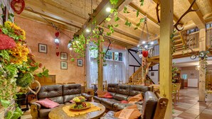 Un intérieur chaleureux et rustique, avec un canapé en cuir, une table ronde en bois et des plantes suspendues.