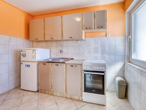Een kleine keuken met een koelkast, oven en wastafel.