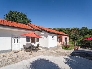 A two-story building with a tiled roof, a patio with outdoor furniture, and a garden area. - Vacation home Franjo by Interhome (Opatija/Ika)