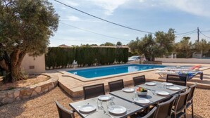 Un espace extérieur aménagé pour les repas, avec une piscine, des murs en pierre et un arbre.