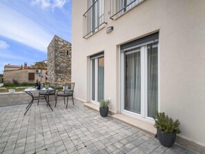Enjoy outdoor dining or relaxation on the patio, surrounded by lush greenery and a stone wall.