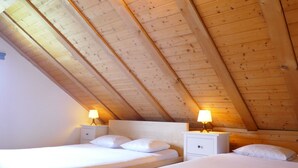 A room with two beds, wooden ceiling beams, and bedside lamps. - Rustico Pamela by Interhome (Malvaglia)