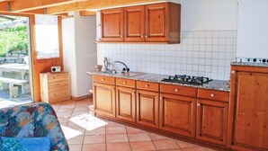 A kitchen with wooden cabinets, a tiled backsplash, and a gas stove. - Rustico Pamela by Interhome (Malvaglia)