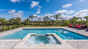 A rectangular swimming pool with a hot tub in the center, surrounded by a paved deck.