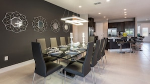 A modern dining area with a glass table, black chairs, and geometric wall art.