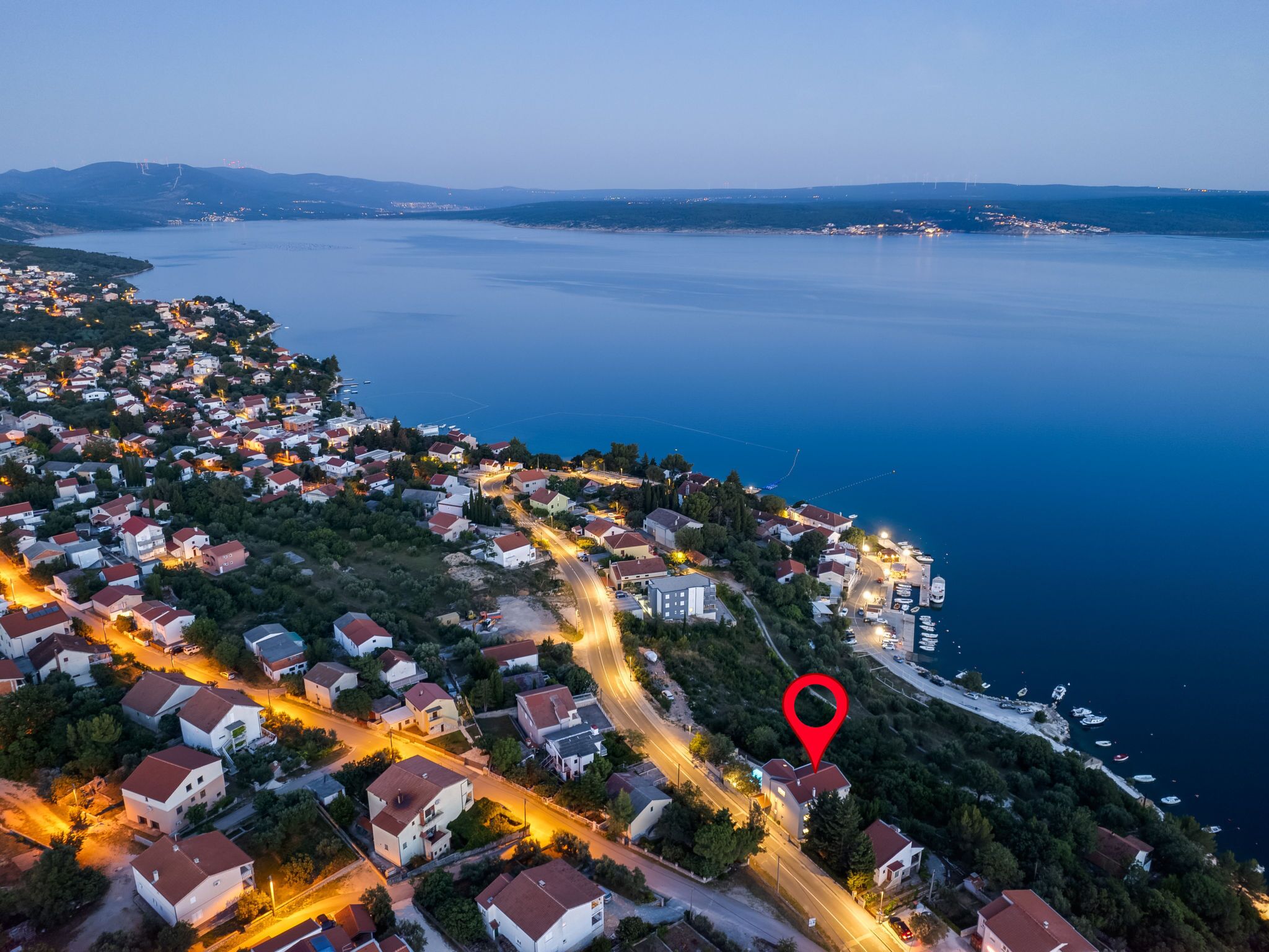 Vue aérienne d’une ville côtière avec ses maisons, ses rues et un port de plaisance.