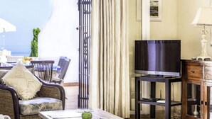 Una sala de estar acogedora con un televisor sobre un mueble bajo, muebles de mimbre y vistas al mar.