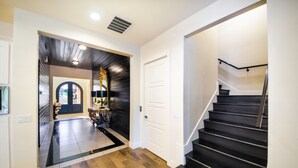 Un interior moderno con suelo de madera, una escalera y un pasillo que conduce a una puerta.