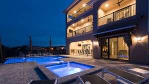 Un hotel de varios pisos con piscina, mobiliario exterior y balcones.