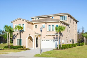 A two-story house with a beige facade, a front entrance with an archway, and a garage.