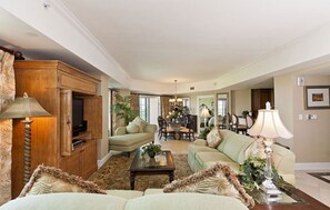 A spacious living room with a large wooden cabinet, two sofas, a coffee table, and a dining area with chairs and a chandelier. - Private Villa 1980 (Kissimmee)
