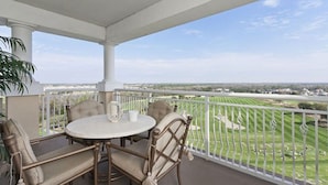 A covered balcony with a round table and four chairs, overlooking a green landscape and distant buildings. - Private Villa 1980 (Kissimmee)
