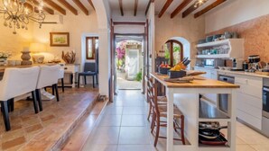 A modern kitchen with wooden beams, a dining area with white chairs, and a chandelier. - Sa Teulera by Interhome (Campanet)