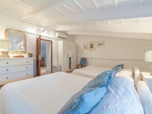 Un dormitorio con dos camas, un aparador, un espejo y una puerta que da a otra habitación.