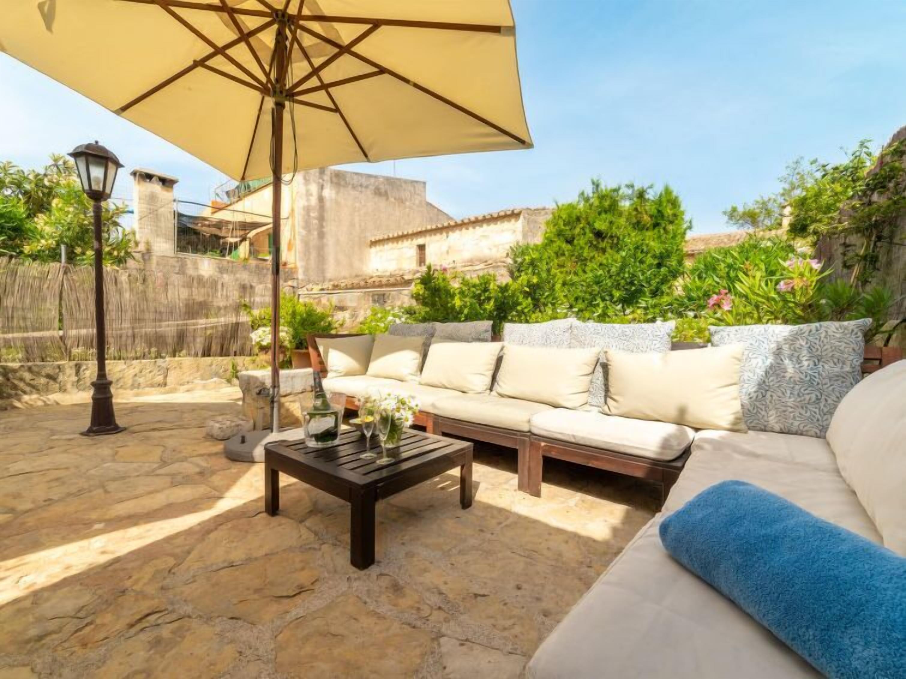 A patio with a beige sofa, a wooden coffee table, and a large umbrella.
