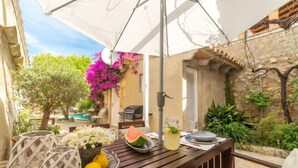 A wooden table with a white umbrella, a grill, and outdoor seating. - Sa Teulera by Interhome (Campanet)