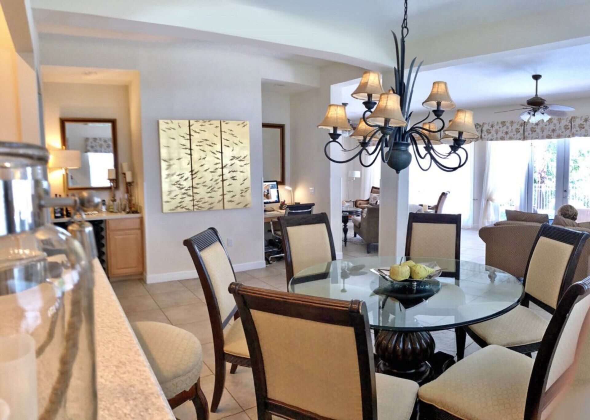 A dining area with a round glass table, six chairs, and a chandelier.