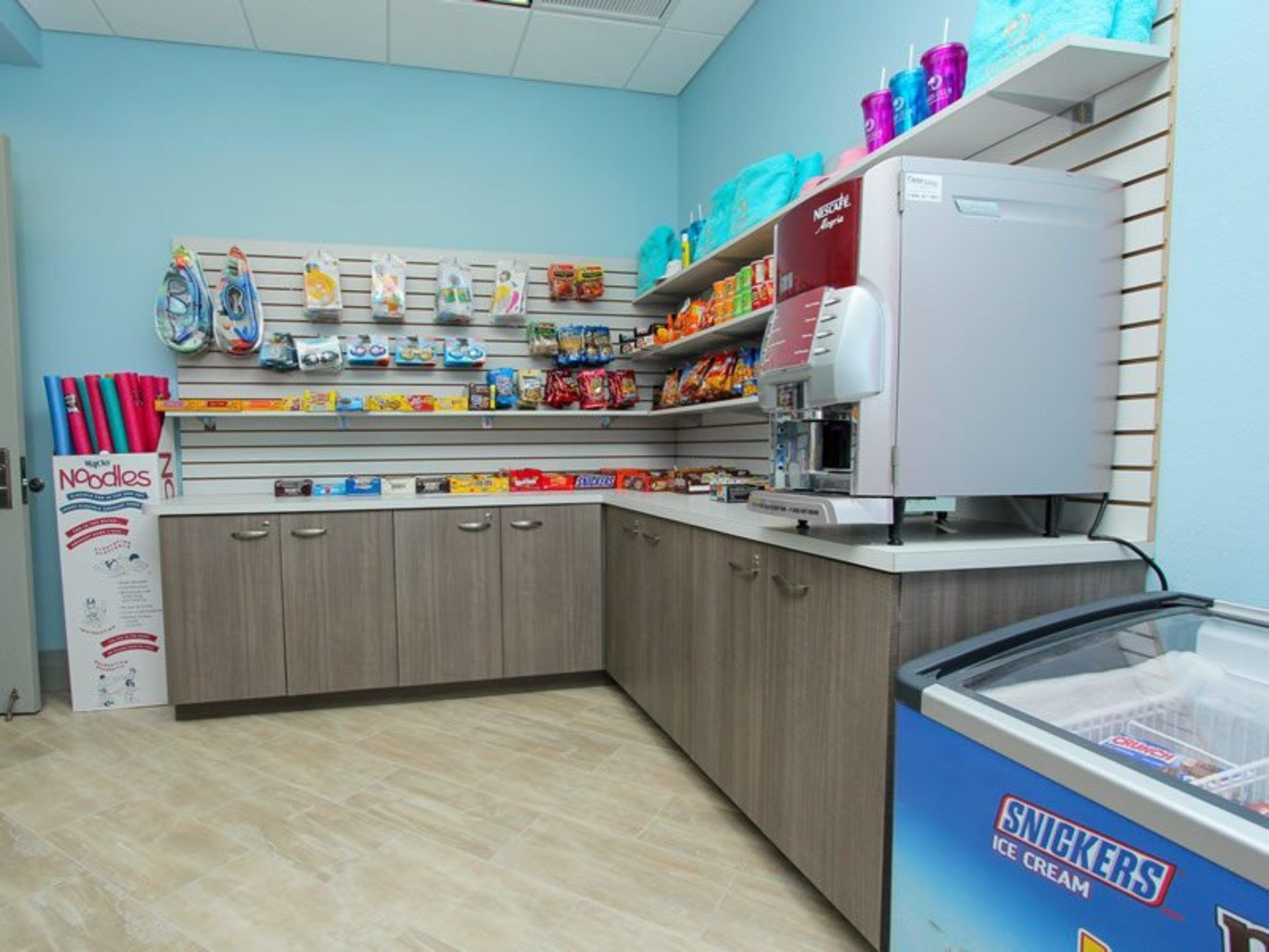 A snack bar with a variety of packaged snacks, a beverage dispenser, and a freezer with ice cream.