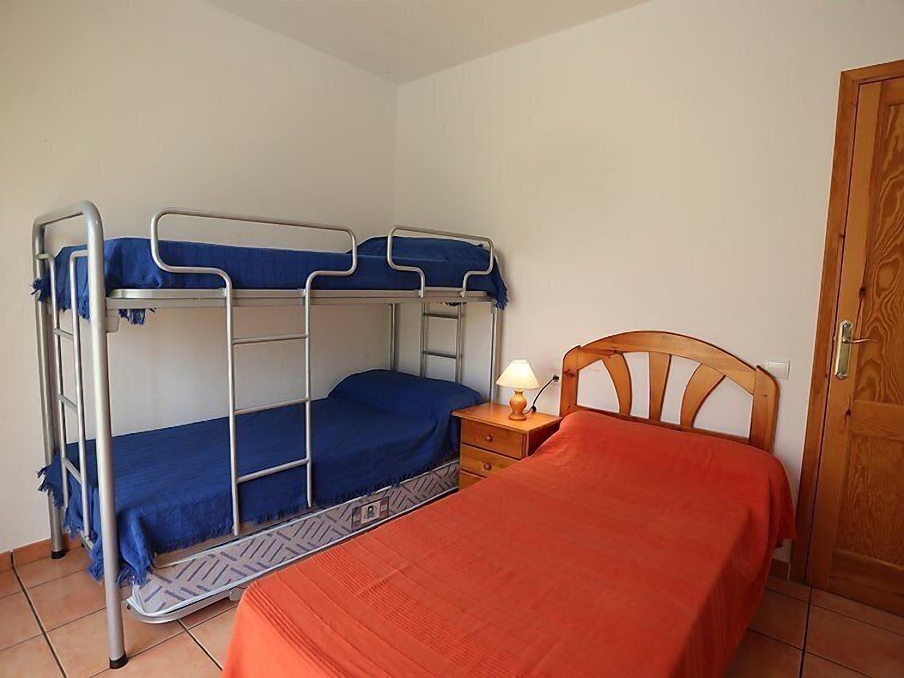 Una camera con un letto a castello, un comodino con una lampada e una porta.