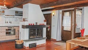 Una cocina rústica con chimenea de piedra, vigas de madera y un comedor con mesa y sillas.