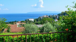 A coastal town with buildings, vineyards, and a clear view of the sea and mountains in the distance. - Apartment Marija by Interhome (Lovran)