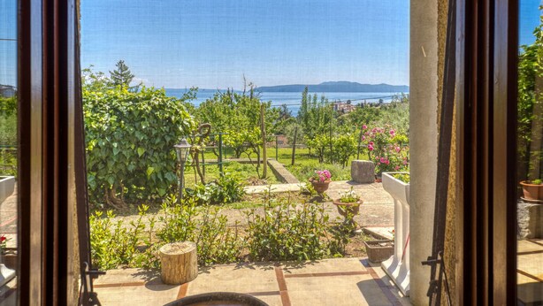 A view from a covered outdoor area with a pergola, potted plants, and a clear view of the sea and distant mountains. - Apartment Marija by Interhome (Lovran)