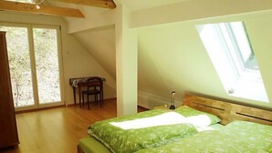 A bedroom with a sloped ceiling, a skylight, a bed with green bedding, a wooden bench, and a chair. - Leubach by Interhome (Wolfach)