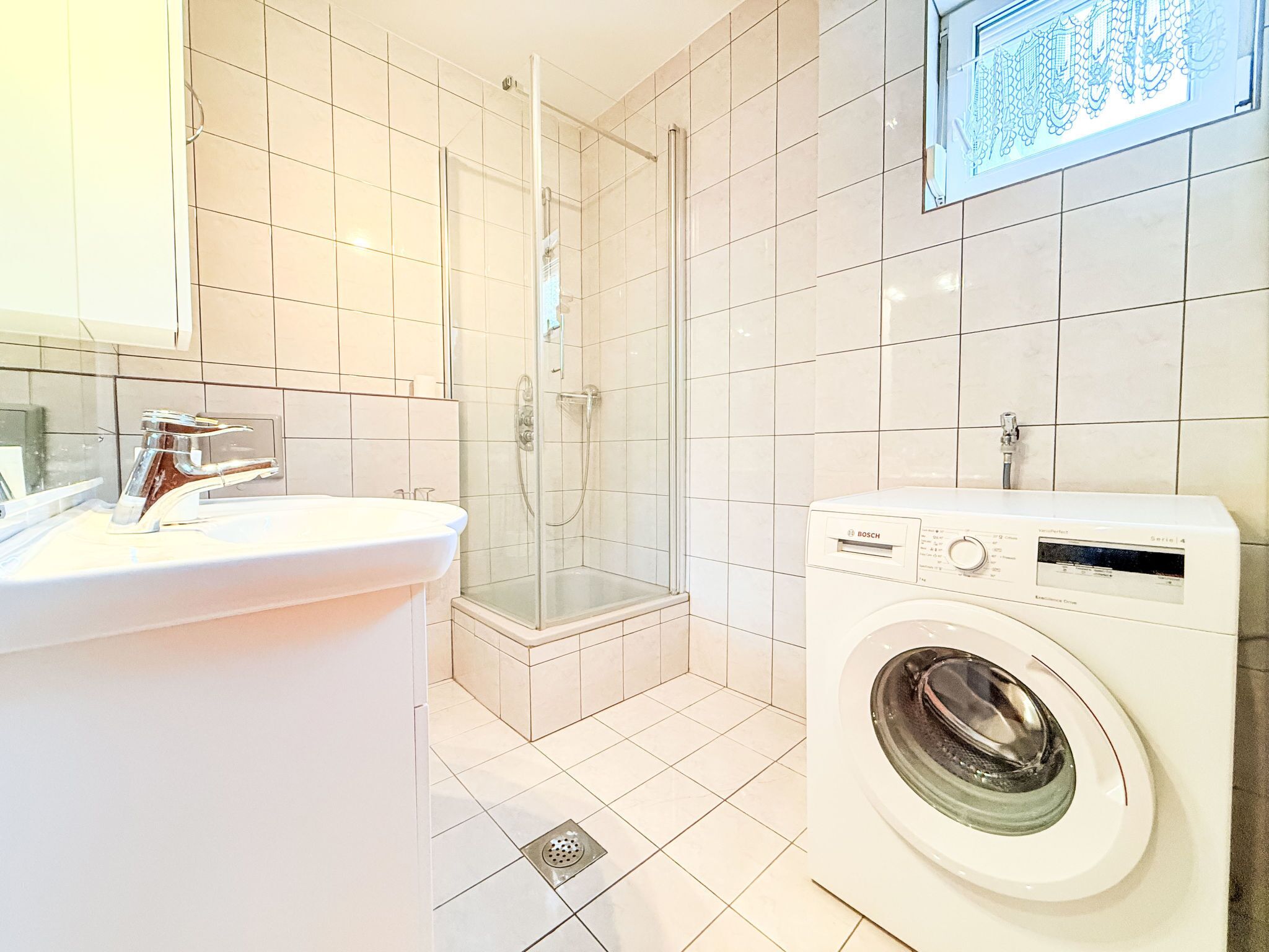Ein modernes Badezimmer mit Waschbecken, Dusche und Waschmaschine.