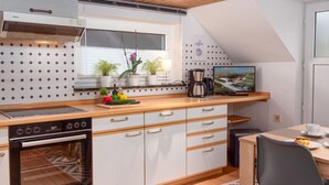 Una cucina moderna con un piano cottura Bosch, una macchina per il caffè e un televisore sul bancone.