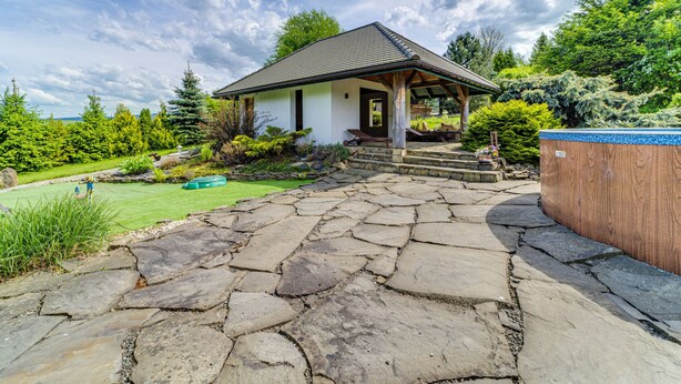 A stone-paved entrance to a house with a covered porch, surrounded by lush greenery and a clear sky. - Vacation home Dworek by Interhome (Rychwald)