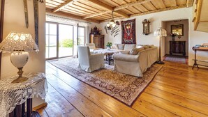A cozy living room with wooden floors, a large rug, and a fireplace. - Vacation home Dworek by Interhome (Rychwald)