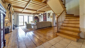 A spacious living room with wooden flooring, a staircase, and a chandelier. - Vacation home Dworek by Interhome (Rychwald)