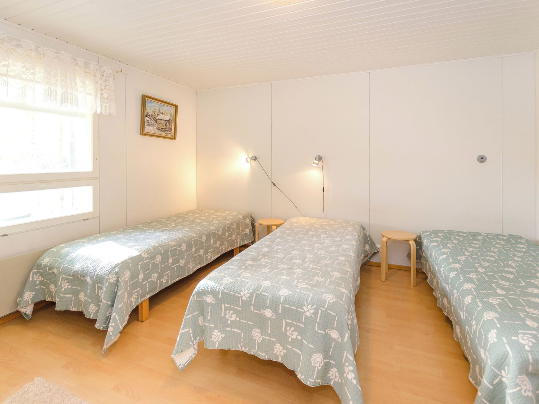 A room with two single beds, a small table, and a window with curtains.