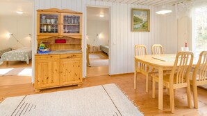 A cozy room with a wooden cabinet, a dining table with chairs, and a bed in the background.