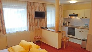 Une chambre d’hôtel avec deux lits, un bureau, une chaise, une télévision et une kitchenette.